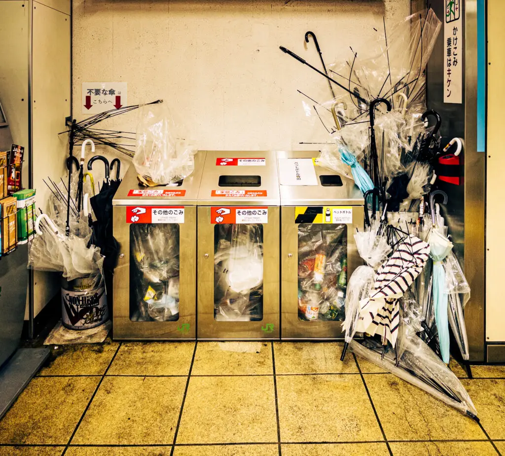 Many broken and discarded umbrellas next to trash receptacles at Yono Station on the Keihin Tohoku Line in Saitama City, Japan
